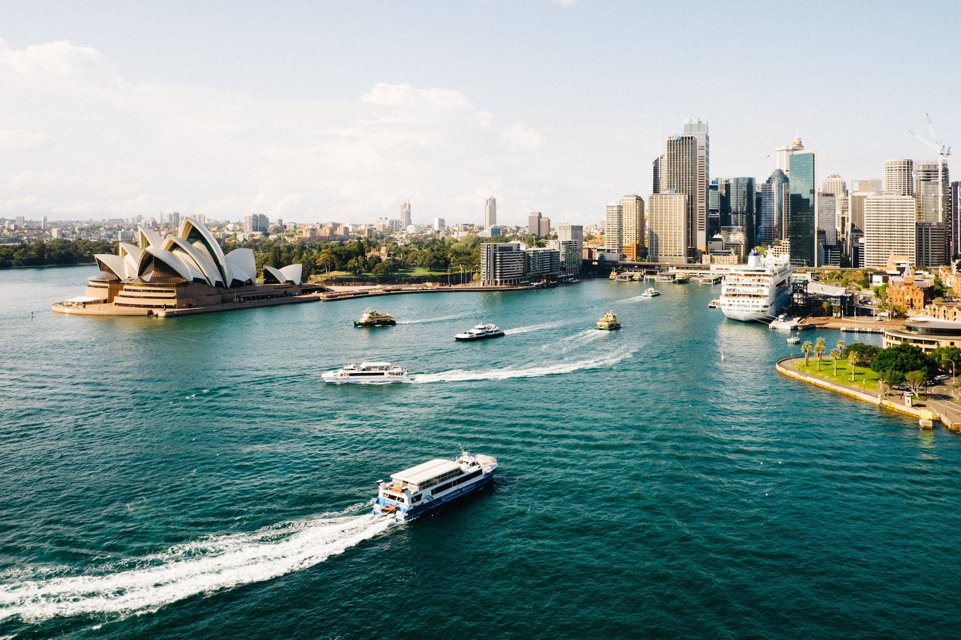 Boats cruising by the Sydney Opera House in the port of this Australian city.
